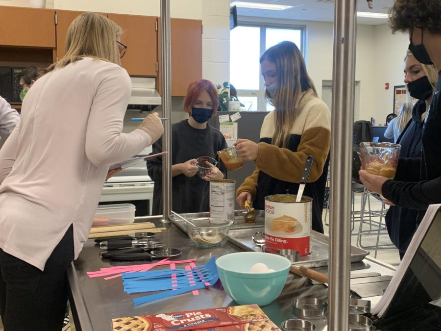 Mrs. Fisher helps two students in her class with a project