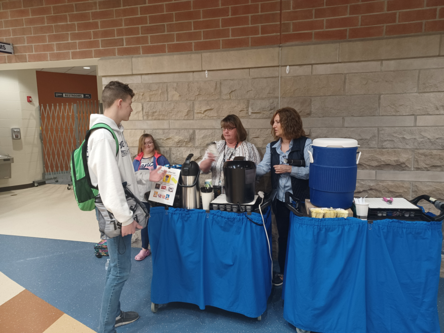 Ms. Dainton (left) and Ms. Collins (right) handing a newly made coffee to a student
