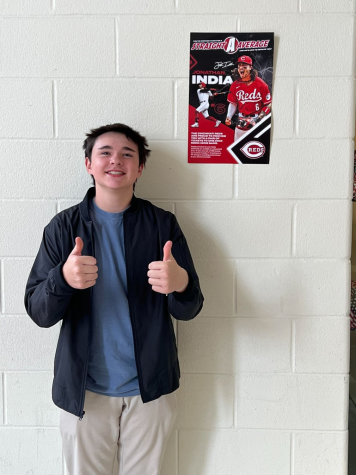 Carson Phillips standing next to a Cincinnati Reds poster