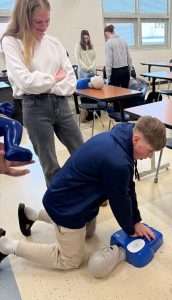 EHS students learn chest compression techniques on a CPR dummy.  