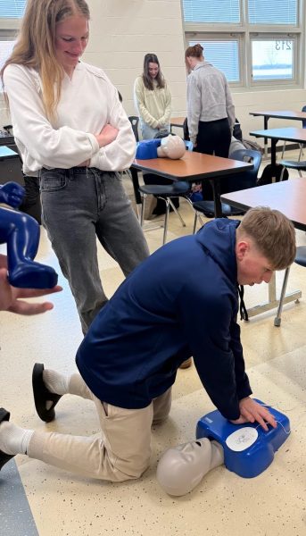 EHS students learn chest compression techniques on a CPR dummy.  